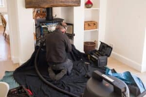 A man wearing protective mask checks a problematic fireplace in a home.